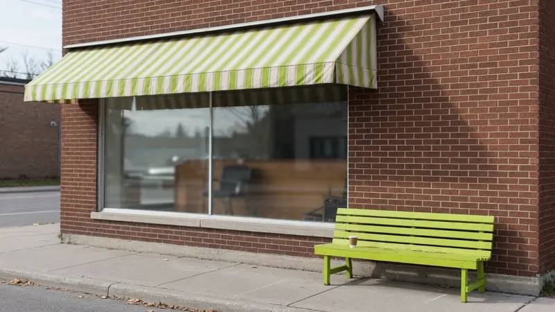 The brick front of a small barbershop with a green striped awning and a lime green bench on the sidewalk